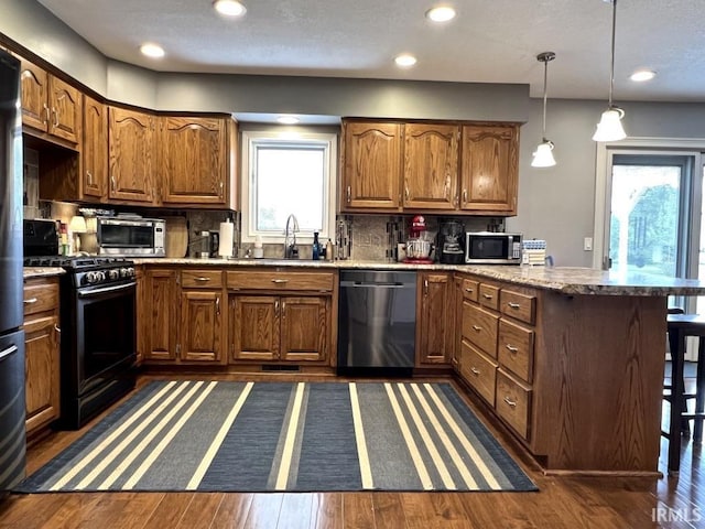 kitchen featuring range with gas stovetop, a peninsula, dishwashing machine, stainless steel microwave, and a sink