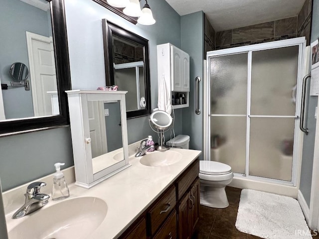 bathroom featuring double vanity, a sink, a stall shower, and tile patterned floors