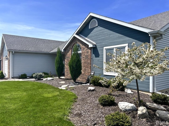 single story home featuring brick siding, a front lawn, and roof with shingles