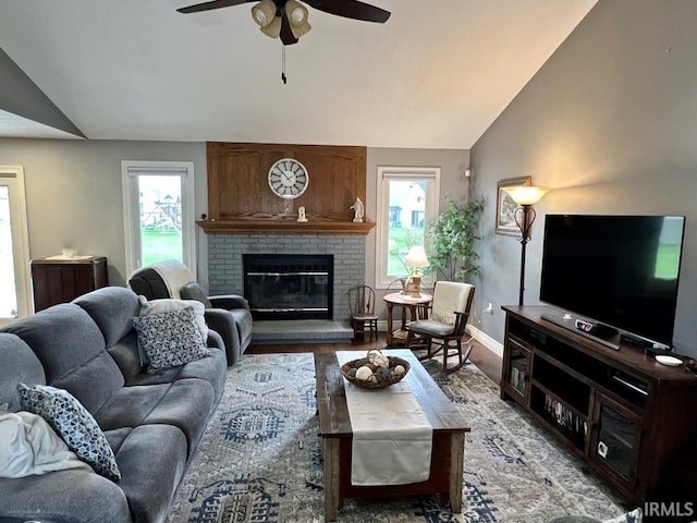 living area featuring ceiling fan, a fireplace, vaulted ceiling, baseboards, and light wood-style floors