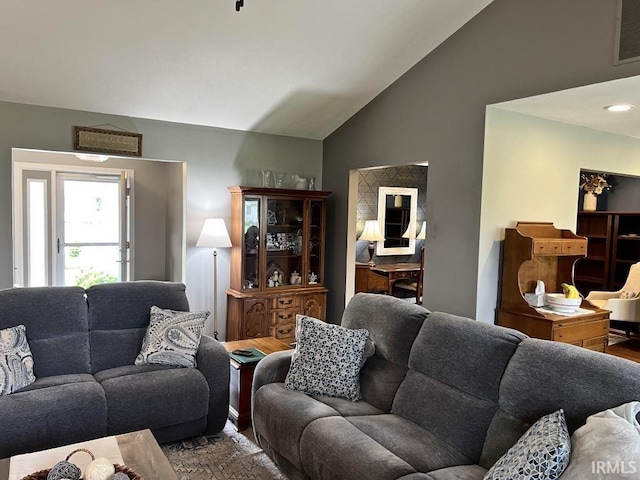 living area with visible vents, wood finished floors, and lofted ceiling