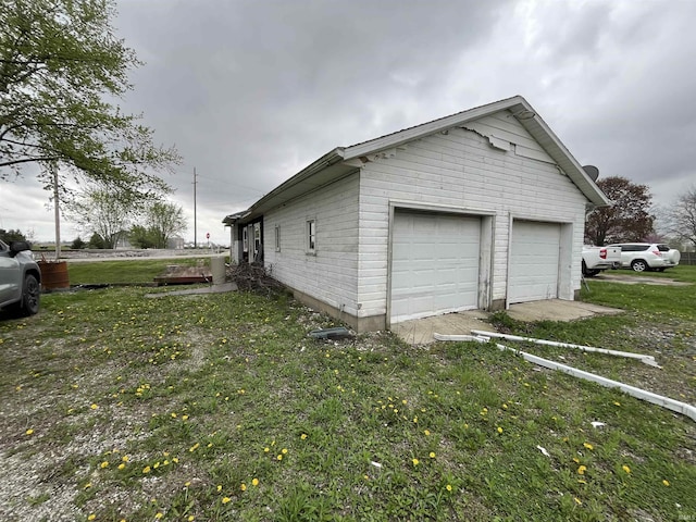 view of property exterior featuring a garage, an outdoor structure, and a lawn