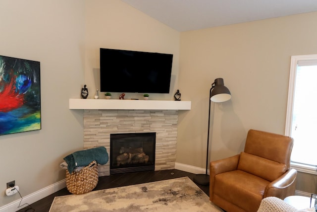 living area with a healthy amount of sunlight, baseboards, a stone fireplace, and wood finished floors