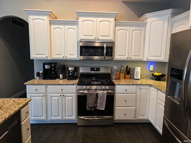 kitchen with white cabinetry, appliances with stainless steel finishes, dark wood finished floors, and light stone counters