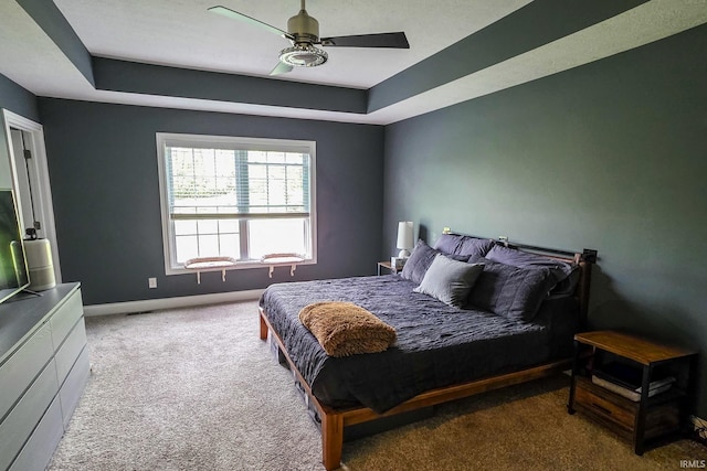 bedroom with baseboards, carpet, ceiling fan, and a tray ceiling