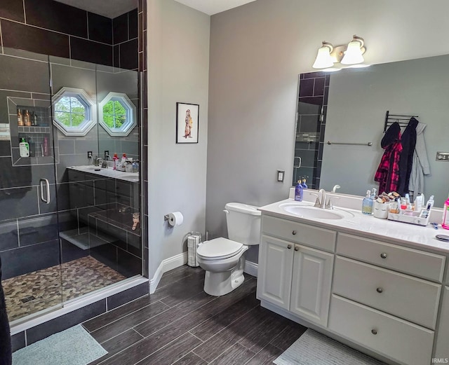 bathroom featuring vanity, toilet, baseboards, wood tiled floor, and a shower stall