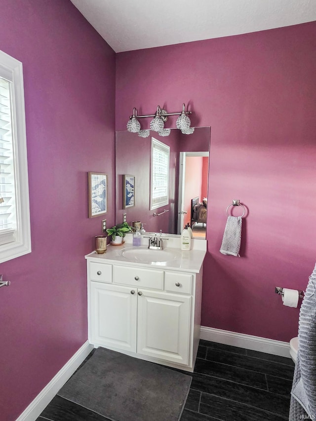 bathroom with toilet, baseboards, wood finished floors, and vanity