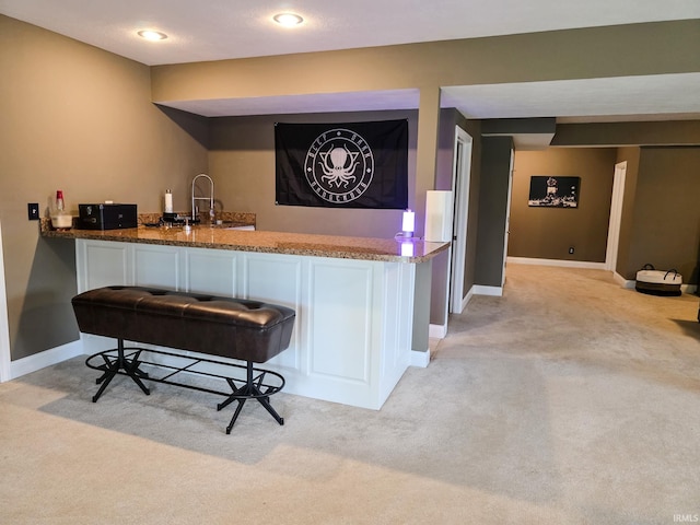bar featuring light colored carpet, a sink, baseboards, and indoor wet bar