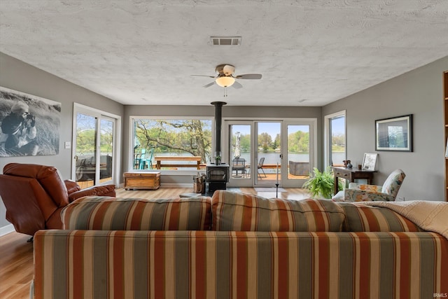 15860 Cook Lake Trl, Plymouth, IN 46563 - living area featuring a wood stove, a ceiling fan, wood finished floors, a water view, and visible vents
