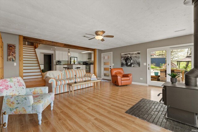 15860 Cook Lake Trl, Plymouth, IN 46563 - living room featuring visible vents, baseboards, stairway, light wood-type flooring, and a ceiling fan