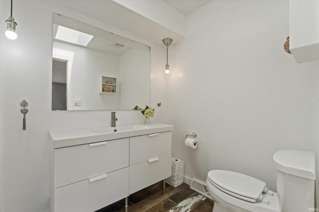 15860 Cook Lake Trl, Plymouth, IN 46563 - half bathroom with a skylight, wood finished floors, vanity, baseboards, and toilet