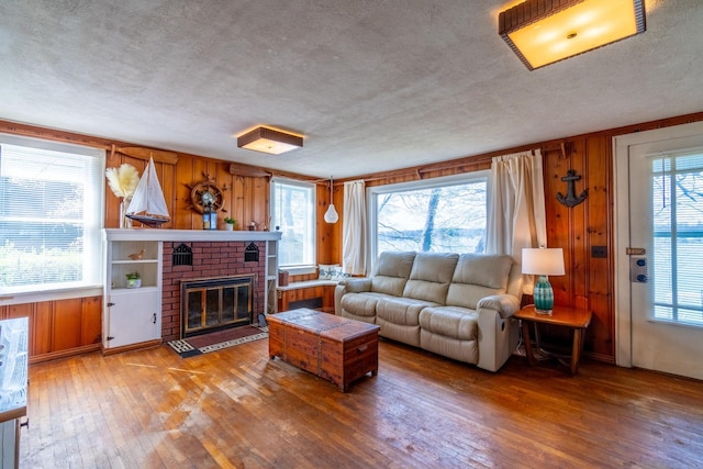 living area with wood-type flooring, a textured ceiling, and wooden walls