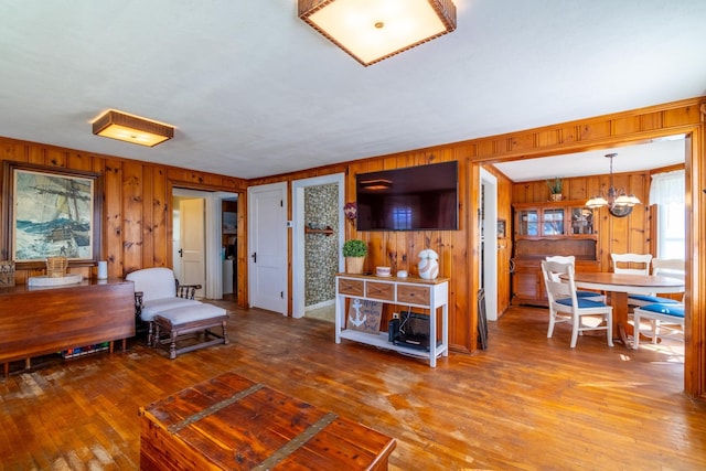 interior space with wooden walls, an inviting chandelier, and hardwood / wood-style floors