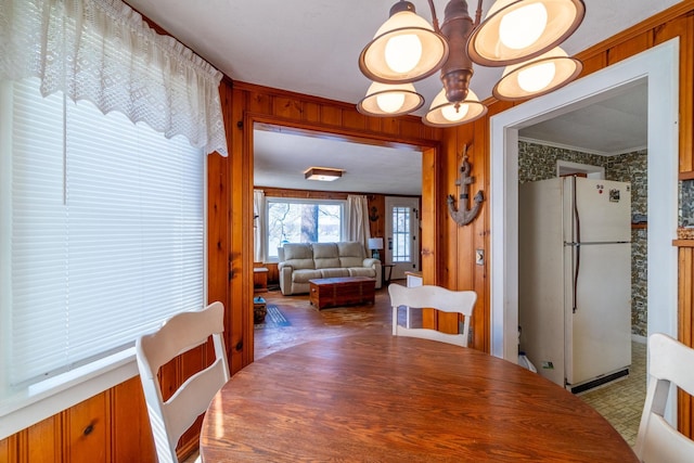 dining space with crown molding, wood walls, and a chandelier