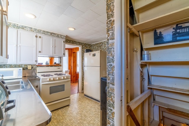 kitchen featuring a sink, light countertops, white cabinets, light floors, and white appliances