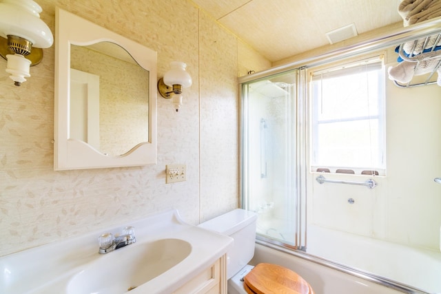 full bath featuring toilet, visible vents, bath / shower combo with glass door, and vanity