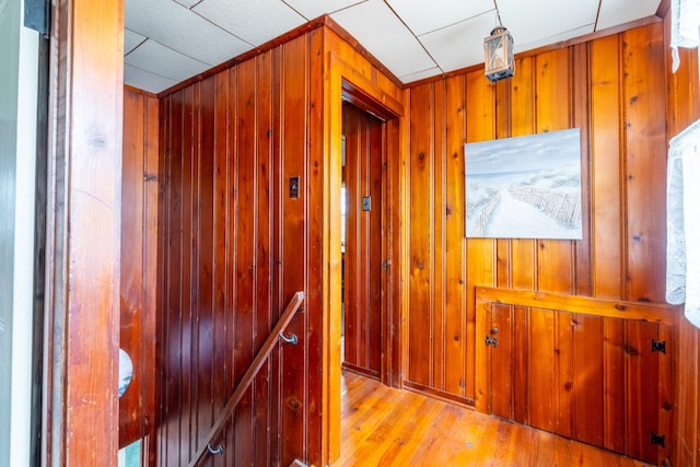 hall featuring wood walls, wood finished floors, and an upstairs landing