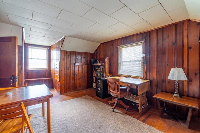 office area featuring wooden walls, vaulted ceiling, and wood finished floors