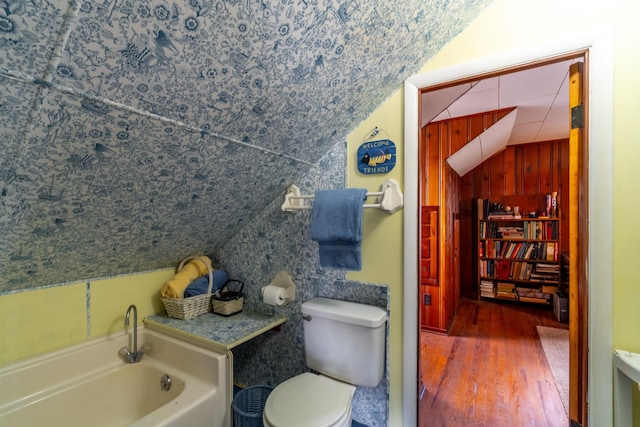full bathroom featuring a bath, vaulted ceiling, toilet, and wood finished floors