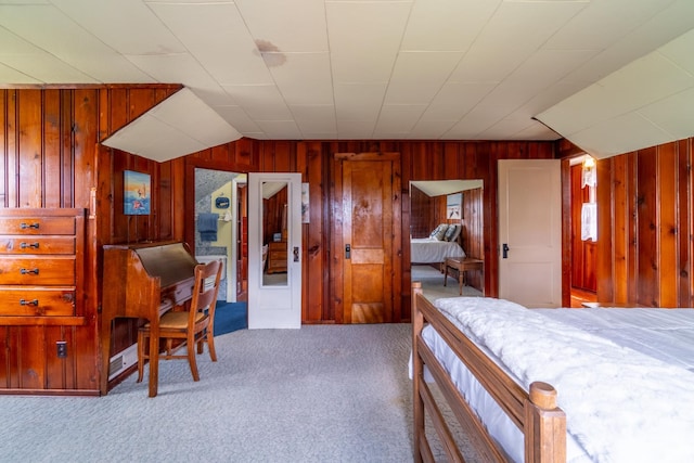 bedroom with carpet flooring and wood walls