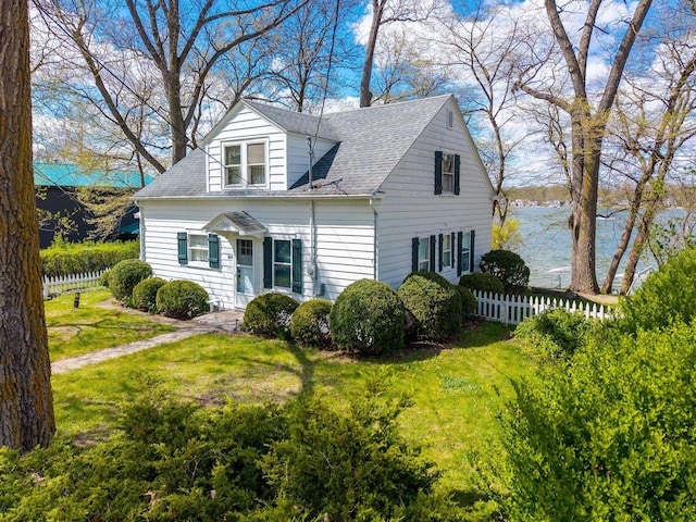view of front of property with a front yard, fence, and roof with shingles