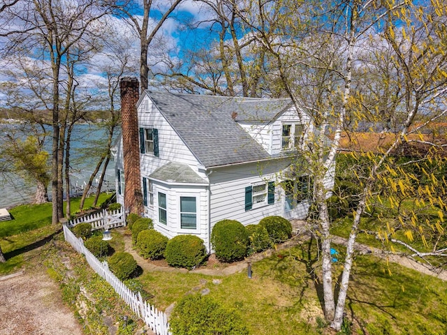 view of front of house with roof with shingles, fence, and a chimney