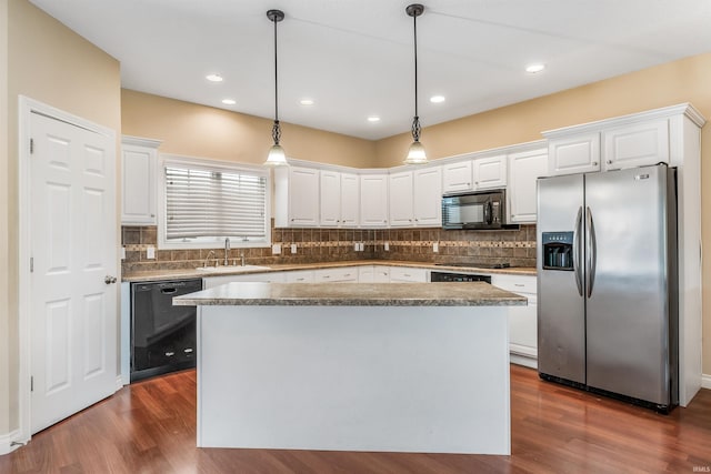 kitchen featuring pendant lighting, white cabinetry, tasteful backsplash, a sink, and black appliances