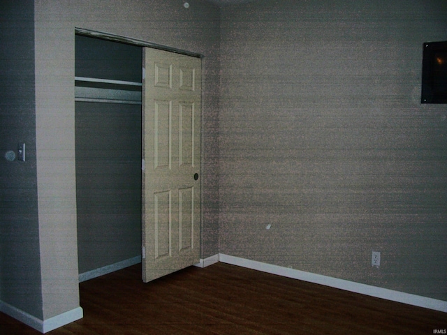 unfurnished bedroom featuring baseboards, wood finished floors, and a closet