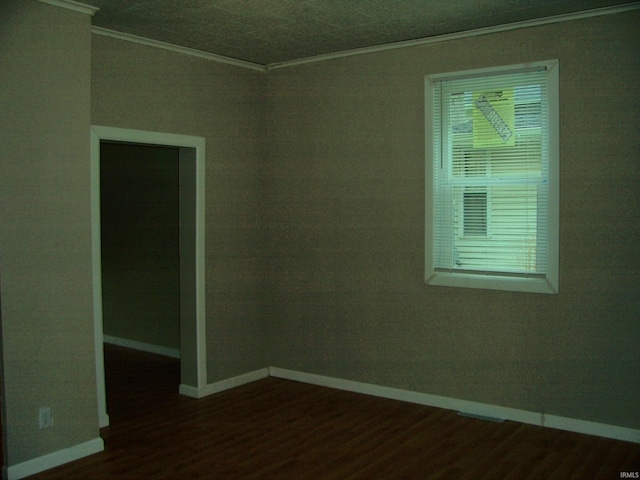empty room with dark wood-style flooring, baseboards, and ornamental molding