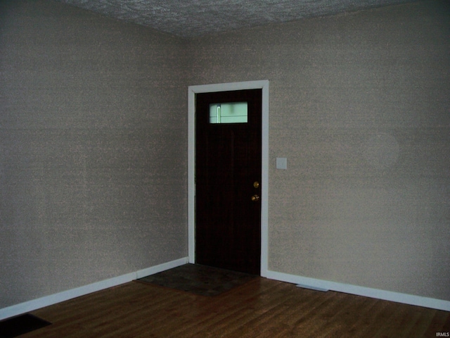 spare room featuring baseboards, dark wood-style floors, and visible vents
