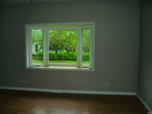 spare room with baseboards and wood finished floors