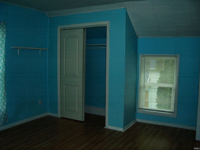 unfurnished bedroom featuring baseboards, a closet, and dark wood-style flooring