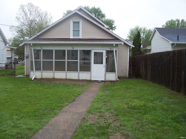 rear view of house with a sunroom, fence, and a yard