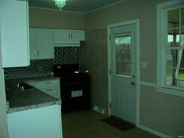 kitchen with decorative backsplash, black range with gas stovetop, white cabinetry, a sink, and light tile patterned floors