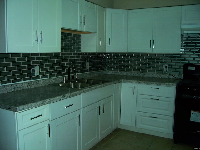 kitchen featuring black gas stove, white cabinetry, a sink, backsplash, and light tile patterned floors