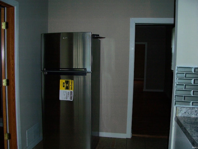 kitchen featuring visible vents, freestanding refrigerator, baseboards, and dark tile patterned flooring
