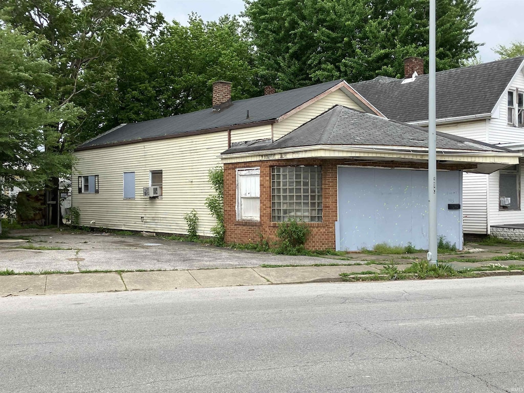 view of front facade featuring a shingled roof, a chimney, and brick siding