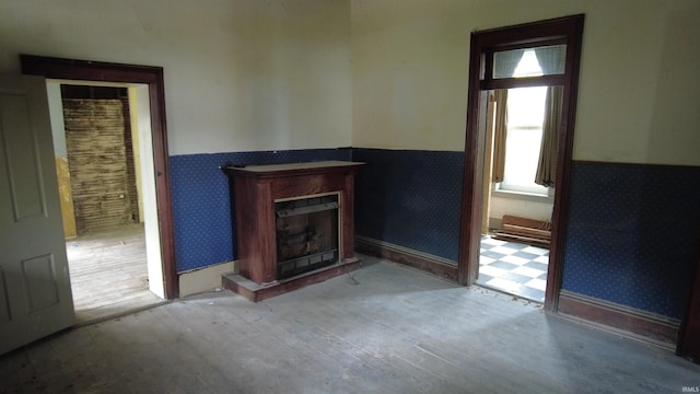 unfurnished living room with wainscoting, wood finished floors, a fireplace, and wallpapered walls