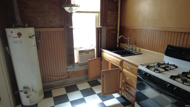 kitchen featuring gas water heater, wainscoting, a sink, light floors, and gas range oven