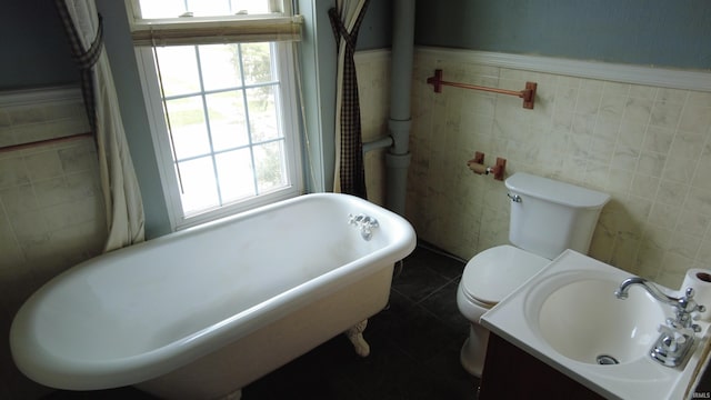 bathroom featuring tile patterned floors, a freestanding bath, a wealth of natural light, and toilet