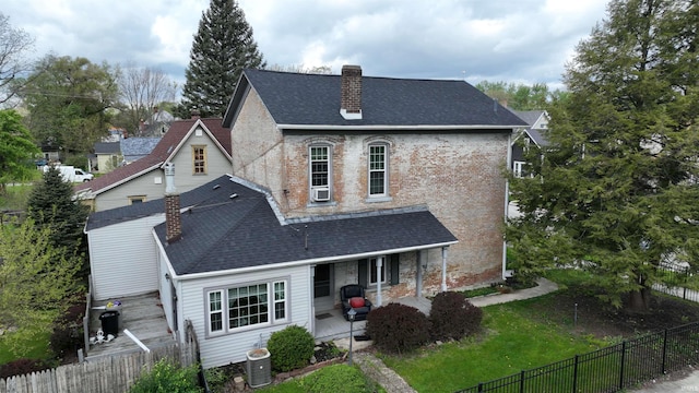 view of front facade featuring a porch, brick siding, fence private yard, and a chimney