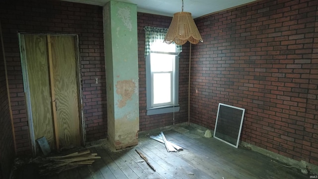 empty room featuring brick wall and hardwood / wood-style floors
