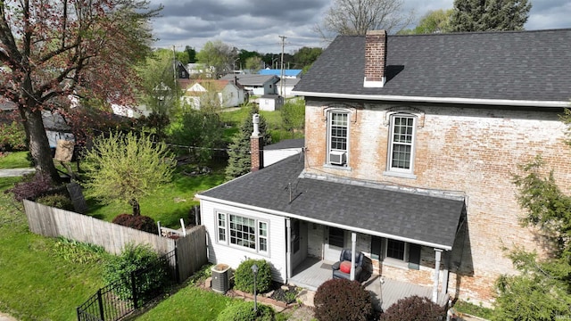 exterior space with a shingled roof, fence, covered porch, and a chimney