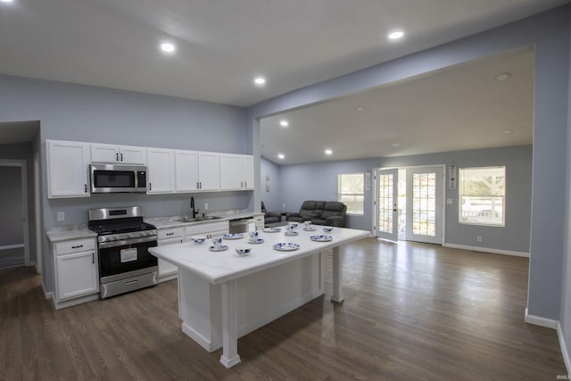 kitchen featuring a sink, white cabinets, stainless steel appliances, and open floor plan