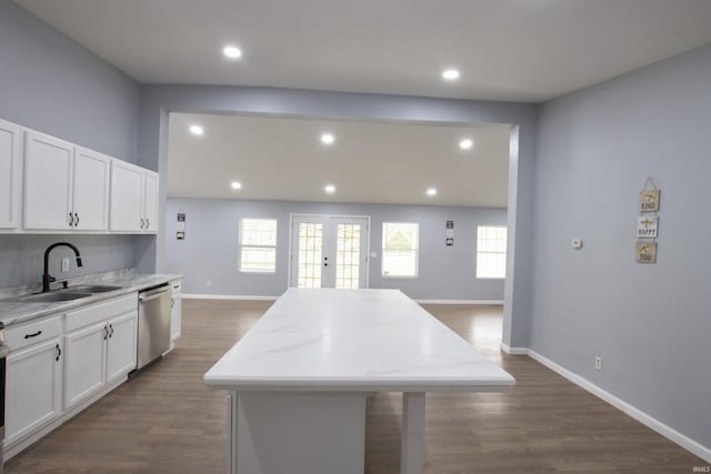 kitchen with white cabinets, a sink, dishwasher, baseboards, and a kitchen island