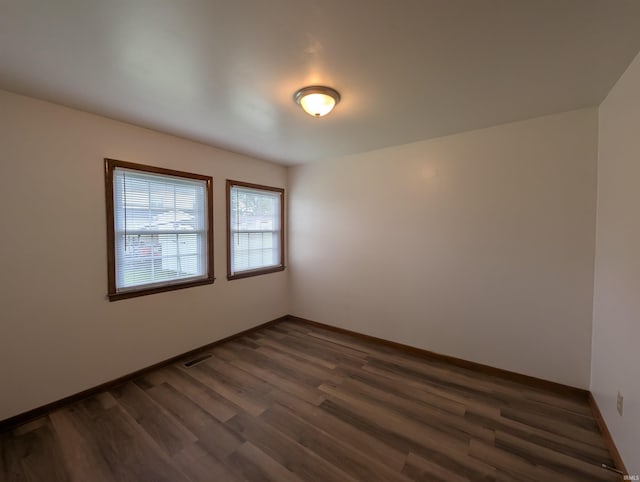 empty room with baseboards, dark wood finished floors, and visible vents