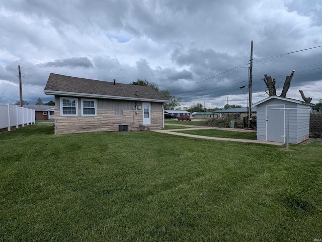 view of yard with an outdoor structure, fence, a shed, and central air condition unit