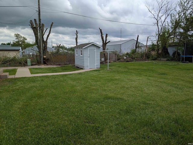 view of yard featuring fence, a trampoline, an outdoor structure, and a shed