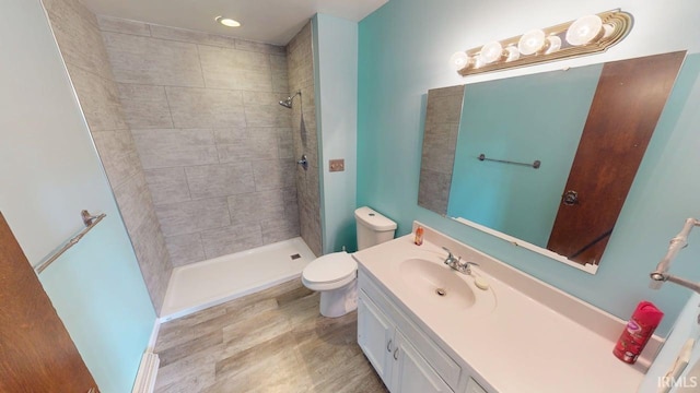 full bathroom featuring vanity, a tile shower, and toilet