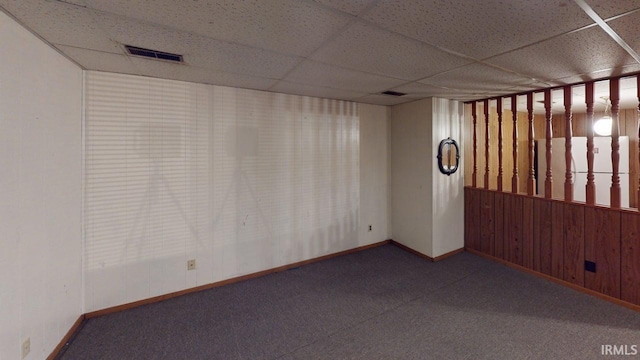 spare room featuring baseboards, visible vents, a paneled ceiling, and carpet